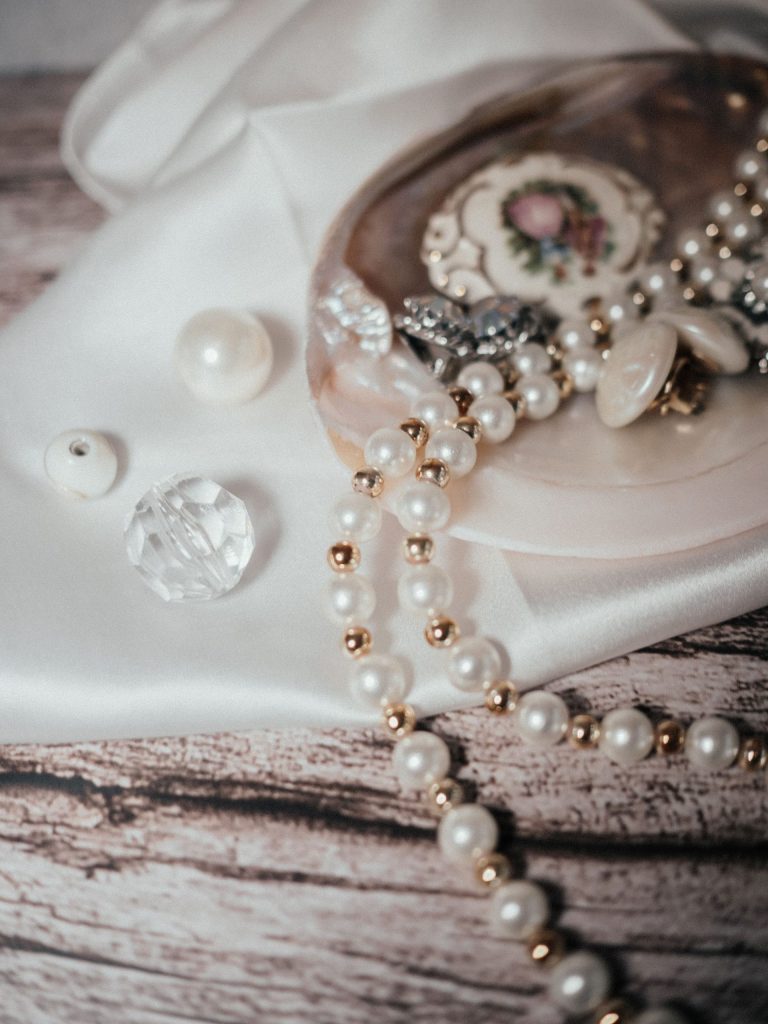 Charming still life featuring pearl jewelry and vintage decorative items on fabric.